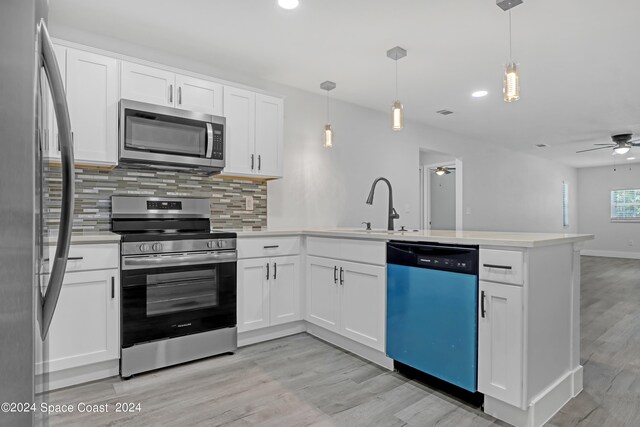 702 S Myrtle Ave, New Smyrna Beach, FL 32168 - kitchen with tasteful backsplash, a sink, light wood-style floors, a peninsula, and appliances with stainless steel finishes