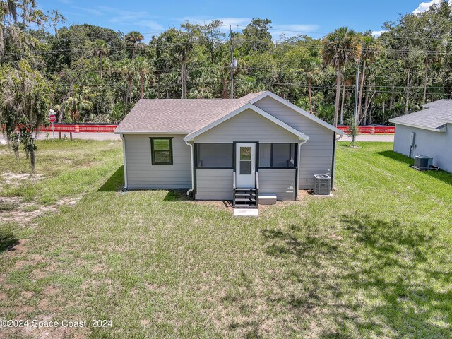 702 S Myrtle Ave, New Smyrna Beach, FL 32168 - view of front of home featuring a shingled roof, a front lawn, central AC unit, and entry steps