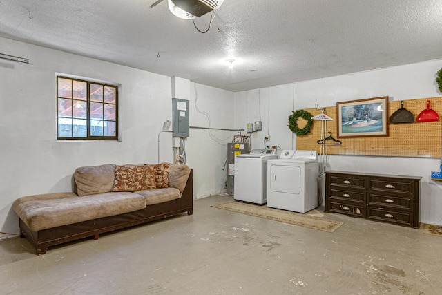 basement with water heater, washer and clothes dryer, and a textured ceiling