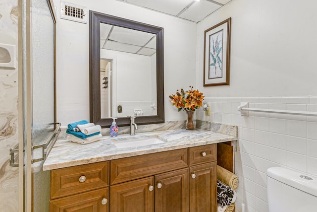 bathroom with tile walls, vanity, and toilet