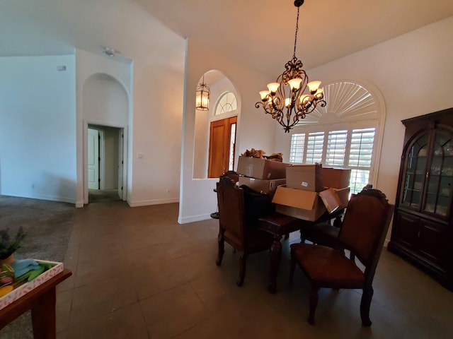 dining space with a chandelier, a towering ceiling, and dark tile patterned flooring