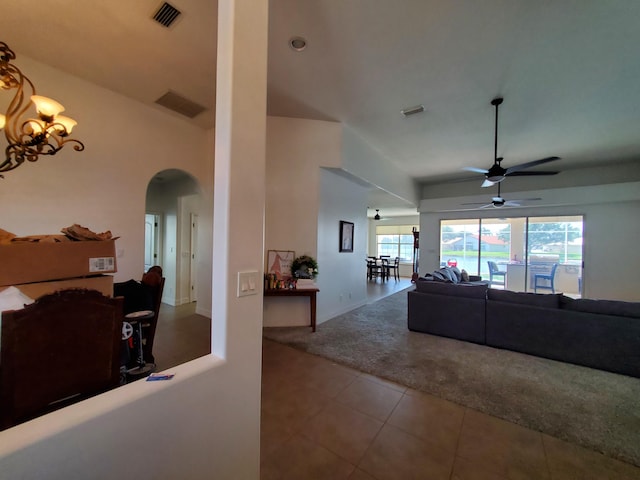 living room with tile patterned flooring and ceiling fan with notable chandelier