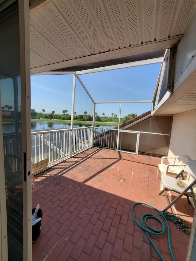 view of patio / terrace featuring a lanai and a water view