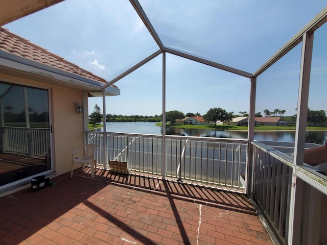 view of patio featuring a water view and glass enclosure