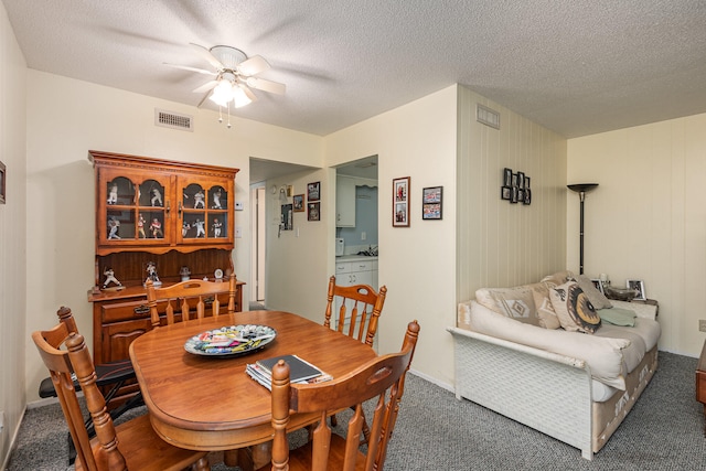 dining area featuring a textured ceiling, ceiling fan, and dark carpet