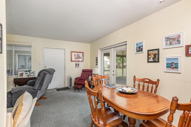 carpeted dining area featuring french doors and a textured ceiling