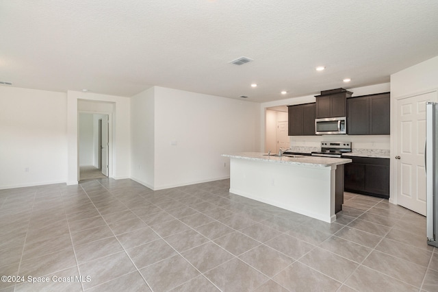 kitchen featuring sink, a textured ceiling, a center island with sink, light tile patterned flooring, and appliances with stainless steel finishes