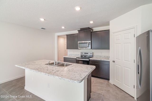 kitchen featuring sink, light tile patterned floors, a kitchen island with sink, and appliances with stainless steel finishes