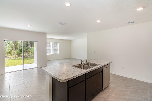 kitchen with sink, stainless steel dishwasher, light tile patterned floors, an island with sink, and dark brown cabinetry