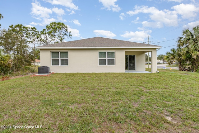 rear view of property with a yard, a patio, and central AC