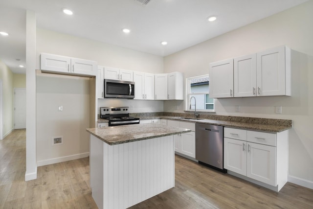 kitchen with light hardwood / wood-style floors, stainless steel appliances, a center island, sink, and white cabinetry