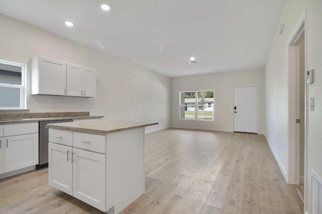 kitchen featuring dishwasher, white cabinetry, light wood-type flooring, and a kitchen island