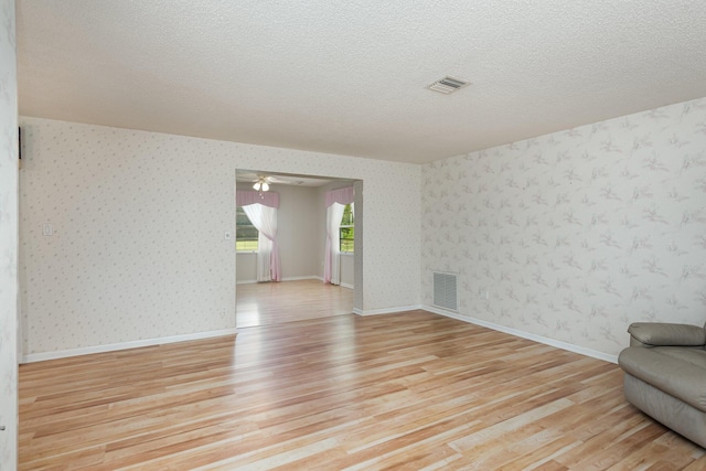 empty room with a textured ceiling and light wood-type flooring