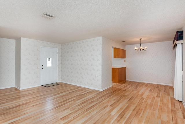 interior space featuring a chandelier, a textured ceiling, and light hardwood / wood-style flooring