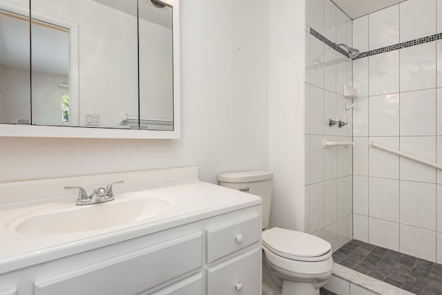 bathroom featuring vanity, toilet, and tiled shower