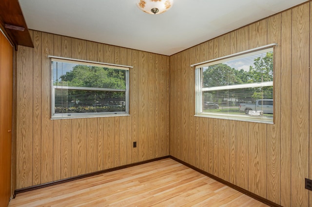 spare room featuring wood walls and light wood-type flooring