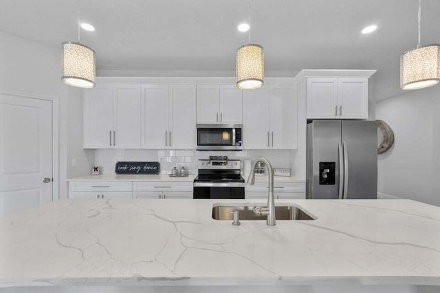 kitchen with appliances with stainless steel finishes, white cabinetry, hanging light fixtures, and sink