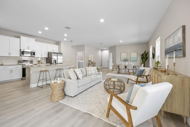 living room featuring sink and light hardwood / wood-style flooring