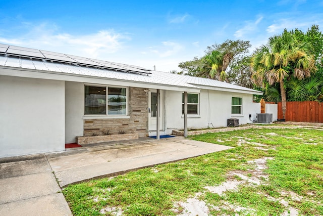 exterior space with a lawn, solar panels, and central air condition unit