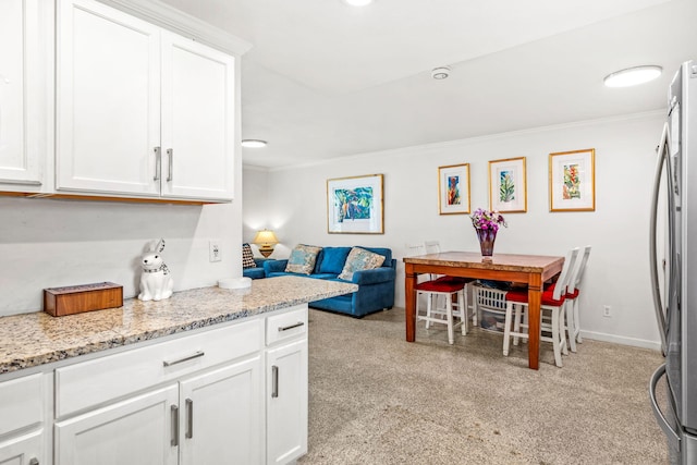 kitchen with light stone countertops, white cabinetry, and light colored carpet