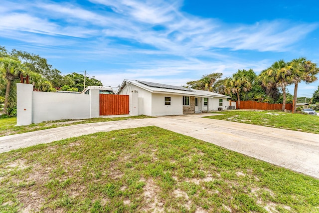 1557 Hillcrest Dr, Melbourne, FL 32935 - view of front of property with a front yard, solar panels, concrete driveway, fence, and stucco siding