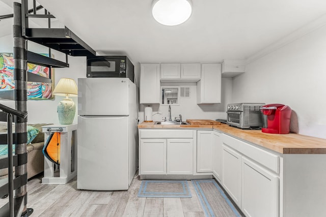 1557 Hillcrest Dr, Melbourne, FL 32935 - kitchen featuring light wood-type flooring, black microwave, freestanding refrigerator, wooden counters, and a sink