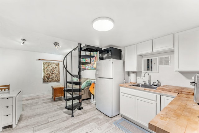 kitchen featuring white refrigerator, white cabinetry, butcher block counters, and sink