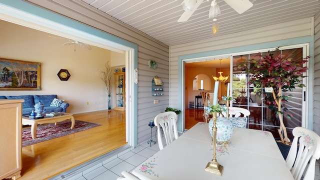 dining room featuring light wood-type flooring, an inviting chandelier, and wooden walls