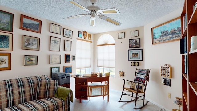 sitting room featuring ceiling fan, light colored carpet, and a textured ceiling