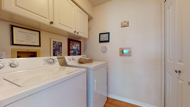 washroom with washing machine and dryer, light hardwood / wood-style flooring, and cabinets