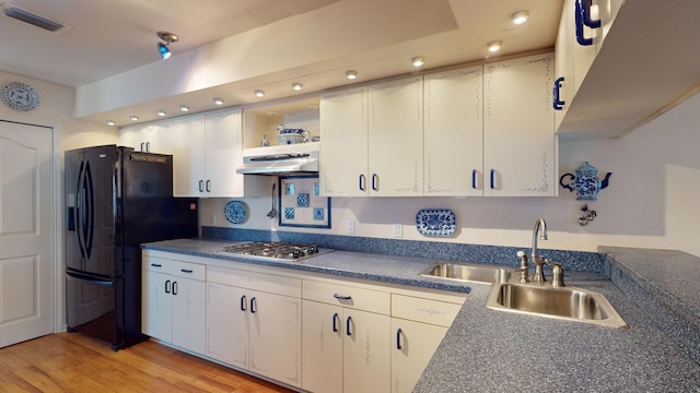 kitchen with stainless steel gas stovetop, black refrigerator with ice dispenser, white cabinets, sink, and light hardwood / wood-style floors