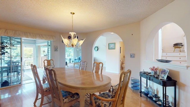 dining space with a chandelier, a textured ceiling, and light hardwood / wood-style floors