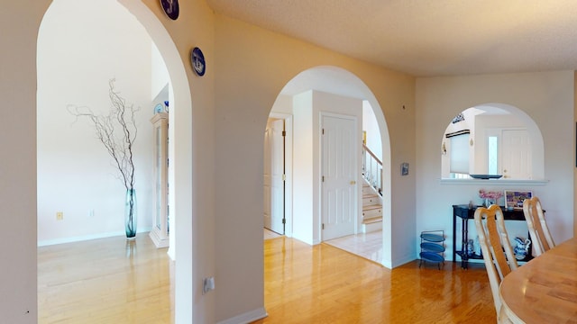 corridor with a textured ceiling and light wood-type flooring