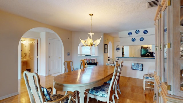 dining area with a chandelier, a textured ceiling, and light hardwood / wood-style floors