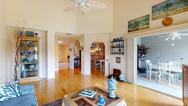 living room featuring ceiling fan, wood-type flooring, and a high ceiling