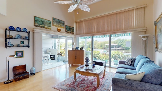 living room with hardwood / wood-style floors, ceiling fan, plenty of natural light, and a high ceiling