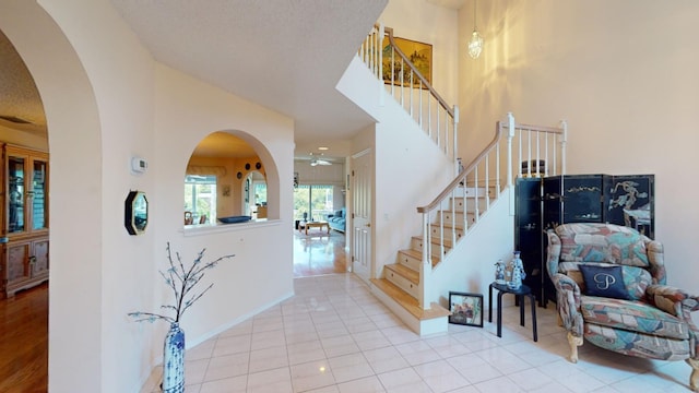 entryway featuring ceiling fan, light tile patterned floors, and a textured ceiling