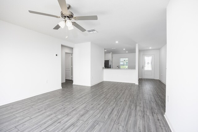 unfurnished living room with sink, ceiling fan, and light hardwood / wood-style flooring