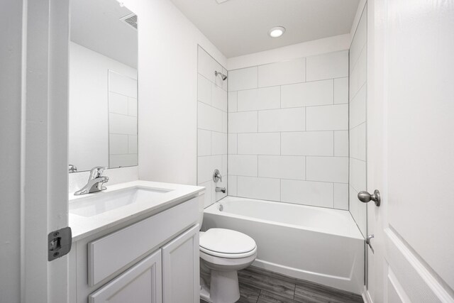 full bathroom with tiled shower / bath, hardwood / wood-style floors, vanity, and toilet