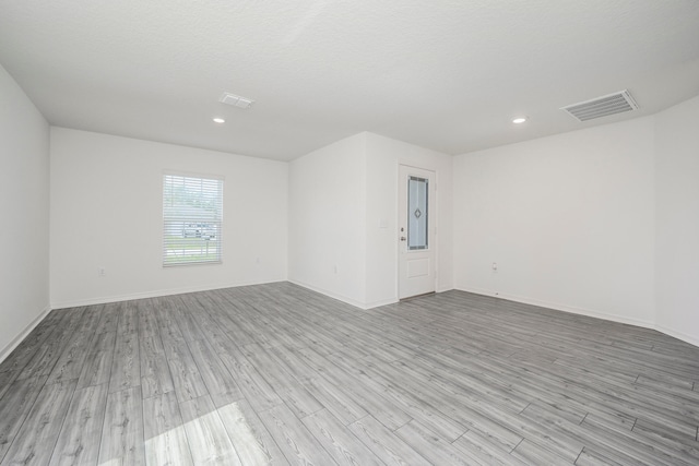 spare room with light hardwood / wood-style floors and a textured ceiling