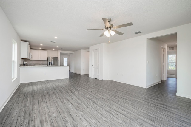 unfurnished living room with ceiling fan, light hardwood / wood-style floors, and a textured ceiling