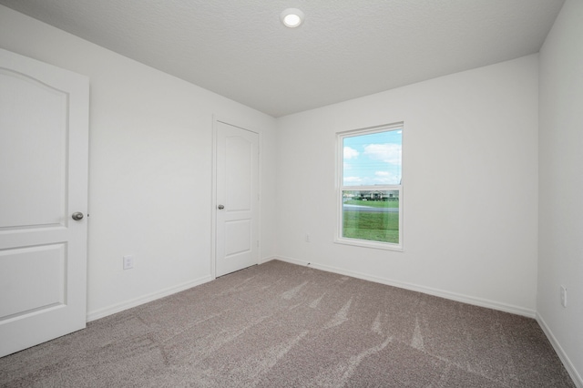 carpeted empty room with a textured ceiling