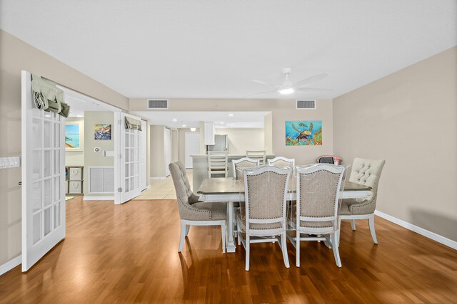 dining space with french doors, wood finished floors, visible vents, and baseboards