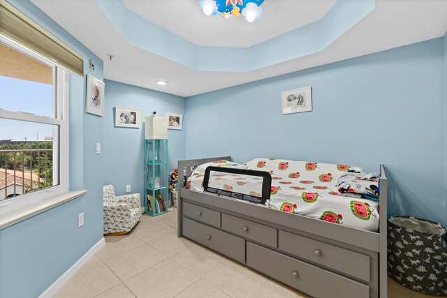 bedroom featuring baseboards, a raised ceiling, and light tile patterned flooring