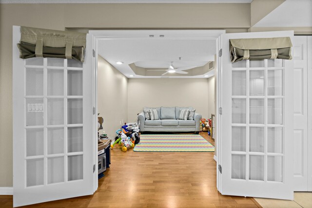 recreation room with a ceiling fan, a tray ceiling, recessed lighting, and wood finished floors