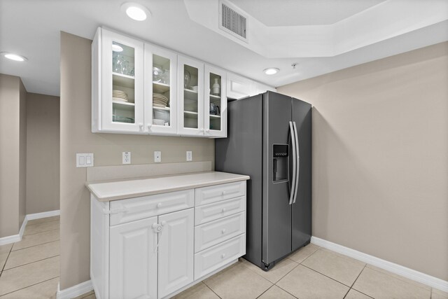 kitchen featuring light countertops, stainless steel fridge, glass insert cabinets, and white cabinets