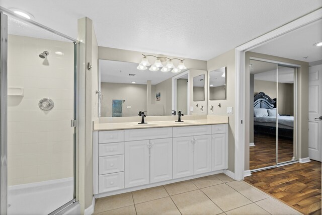 full bathroom featuring a stall shower, a sink, ensuite bath, and double vanity