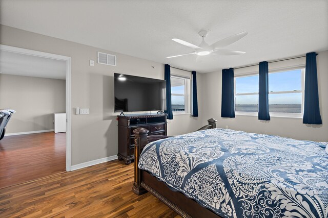 bedroom with baseboards, visible vents, ceiling fan, and dark wood-type flooring