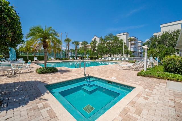 community pool with a patio, a community hot tub, and fence