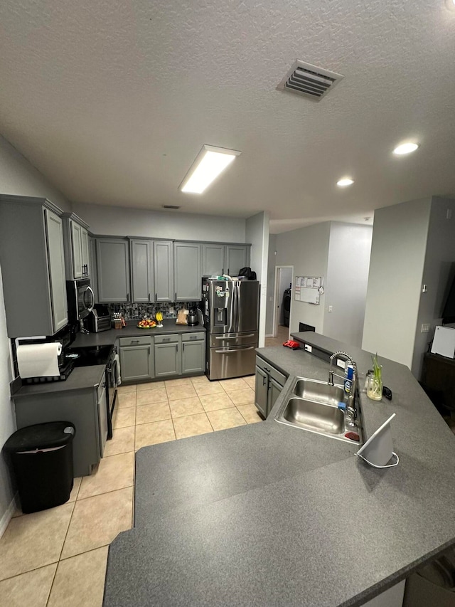 kitchen with gray cabinetry, stainless steel appliances, kitchen peninsula, sink, and light tile floors